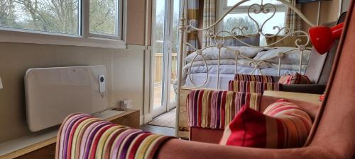 a room with a chair and a bed with a window at Riverside Cabin in Shropshire in Oswestry
