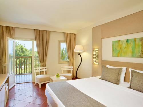 a hotel room with a bed and a balcony at Hapimag Sea Garden Resort in Yaliciftlik