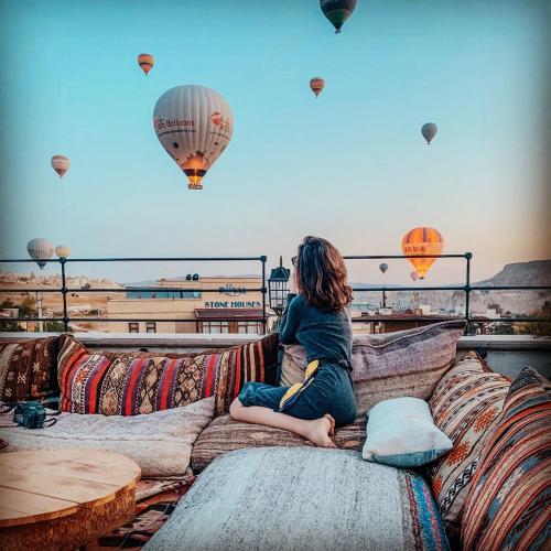 a woman sitting on a couch watching hot air balloons at Caravanserai Inn Hotel in Goreme