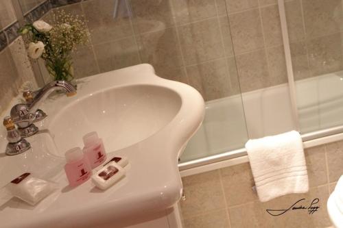 een badkamer met een wastafel en een bad bij Grand Hotel Libertad in Nueve de Julio