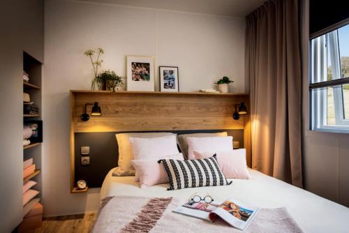 a bedroom with a bed with a book on it at Camping Le Parc de Paris in Villevaudé