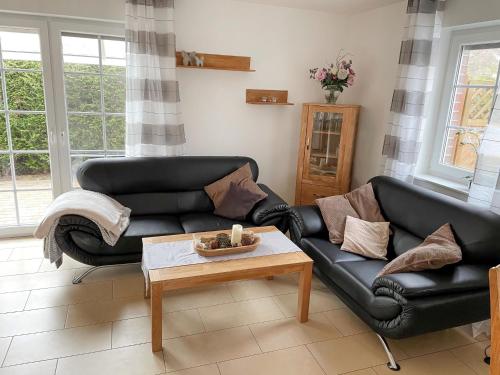 ein Wohnzimmer mit zwei schwarzen Ledersofas und einem Couchtisch in der Unterkunft Holiday Home Deichhuus Een by Interhome in Neßmersiel
