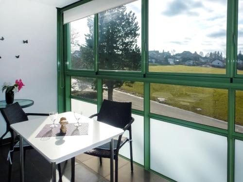 einen weißen Tisch und Stühle in einem Zimmer mit Fenstern in der Unterkunft Apartment B 97 by Interhome in Dittishausen