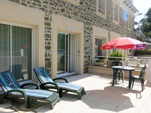 a patio with chairs and a table with an umbrella at Apartment Les Sternes - PGX304 by Interhome in Planguenoual