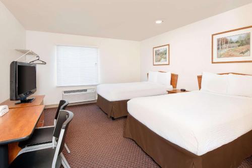 ein Hotelzimmer mit 2 Betten und einem Schreibtisch in der Unterkunft WoodSpring Suites Columbus Fort Moore in Columbus