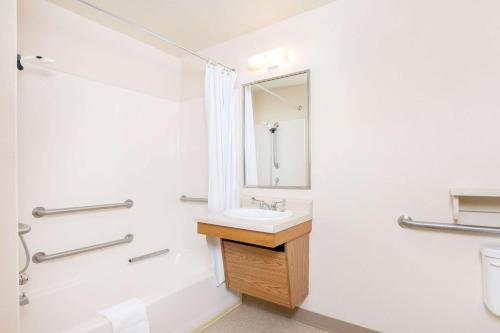 a bathroom with a sink and a mirror at WoodSpring Suites Columbus Fort Moore in Columbus