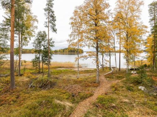 a path through a forest next to a lake at Holiday Home Ranta 3 by Interhome in Vääksy