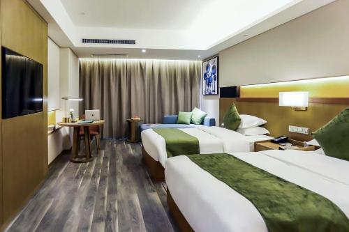una camera d'albergo con due letti e una televisione di Quality Hotel Zhangye a Zhangye