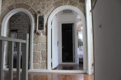a hallway with two mirrors and a stone wall at Eski Tas Hotel in Cesme