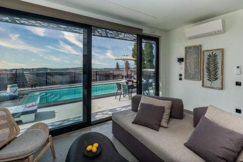 a living room with a couch and a swimming pool at Erolidae Villas in Atsoupádhes