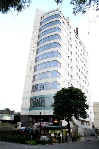 Un edificio alto con un árbol delante. en Shalimar Tower Hotel Lahore, en Lahore