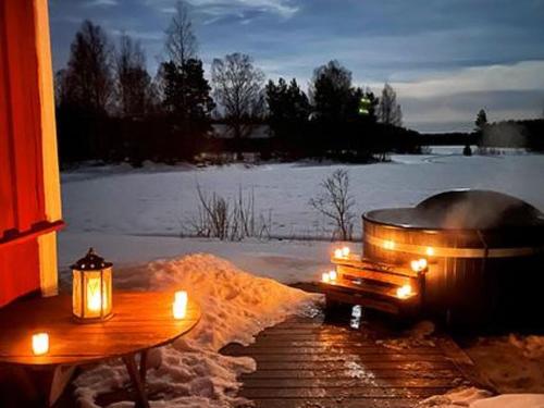 uma banheira de hidromassagem com velas e uma mesa na neve em Holiday Home Virtaan väentupa by Interhome em Nuoramoinen
