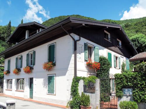 a white house with green shuttered windows and flowers at Apartment Villa Margherita-3 by Interhome in Anduins
