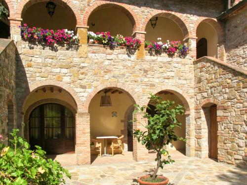 a stone wall with flowers in a courtyard at Apartment Cellole - La Stalla by Interhome in Castellina in Chianti