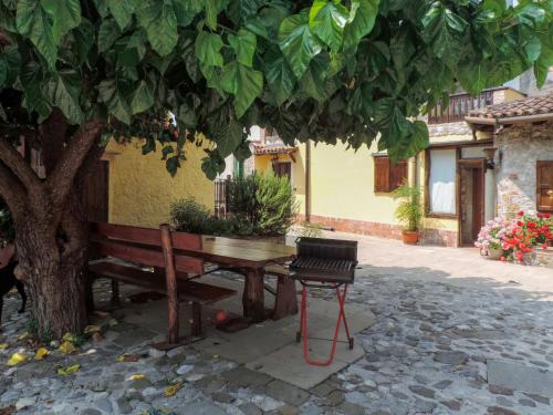 un banco de madera sentado bajo un árbol al lado de un edificio en Holiday Home Al Rustico by Interhome, en San Giovanni al Natisone