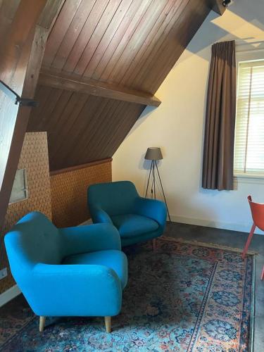a living room with a blue chair and a lamp at Slot Oostende in Goes