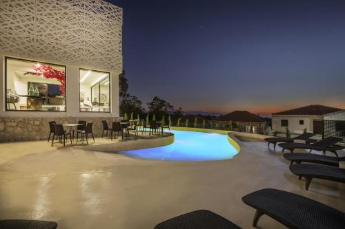 a swimming pool at night with tables and chairs at Erolidae Villas in Atsoupádhes