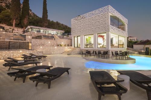 a pool with a bunch of chairs and a building at Erolidae Villas in Atsoupádhes