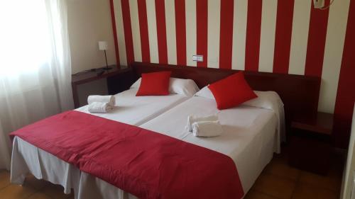 a bedroom with a large bed with red and white pillows at Hostal San Andrés in Soria