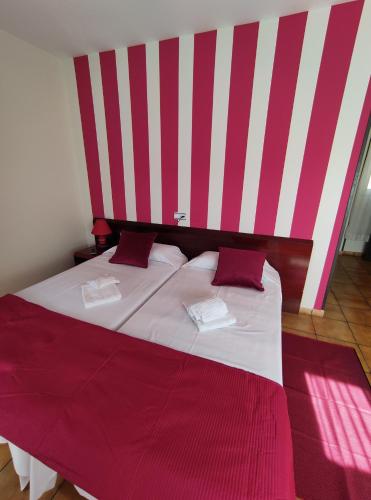 a bedroom with a large bed with red and white stripes at Hostal San Andrés in Soria