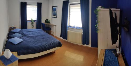 Schlafzimmer mit einem Bett mit blauer Bettwäsche und Fenstern in der Unterkunft Gästehaus 24 in Grettstadt