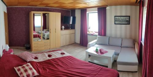 1 dormitorio con cama roja y sala de estar en Gästehaus 24, en Grettstadt