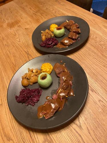 two plates of food on top of a wooden table at Hôtel Dents de Veisivi in Haudères