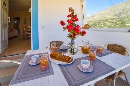 - une table avec des aliments pour le petit-déjeuner et un vase de fleurs dans l'établissement Emmanuela House with garden & sea view - Triopetra, à Triopetra