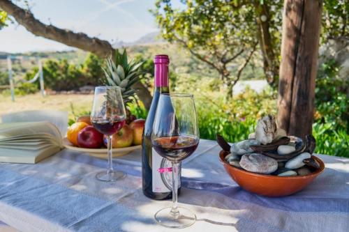 a bottle of wine and two glasses on a table at Emmanuela House with garden & sea view - Triopetra in Triopetra