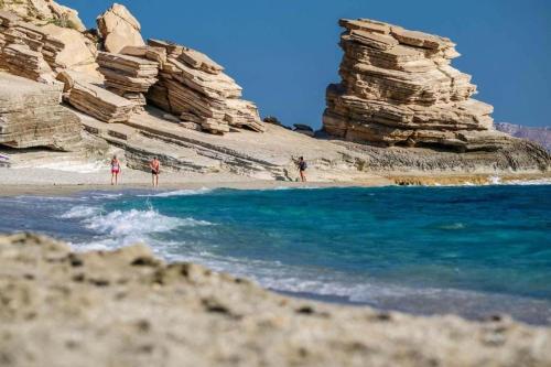a group of people standing on a beach near the water at Emmanuela House with garden & sea view - Triopetra in Triopetra