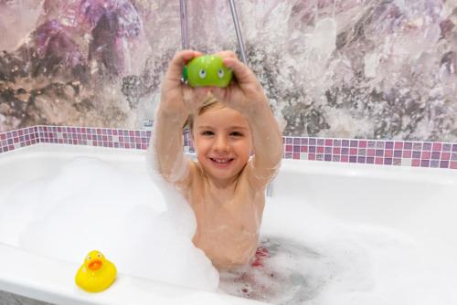 a little girl is playing with a toy in the bathtub at Hotel Sommerhof in Gosau