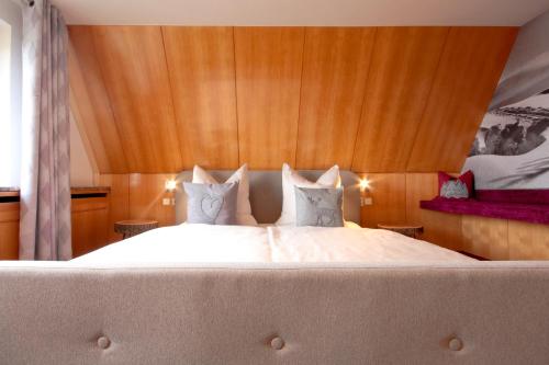a bedroom with a large white bed with wooden walls at Haus am Berg - Pension direkt am Skihang in Kurort Oberwiesenthal