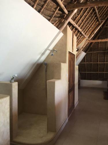 an attic room with a white ceiling and a door at The Loft Zanzibar Kikadini Beach in Jambiani