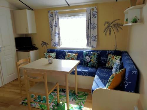 a living room with a blue couch and a table at Camping Cap Soleil île d'Oléron 4 étoiles in La Bétaudière