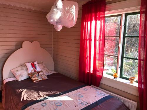 a bedroom with a bed and a window with red curtains at Fisherman s Cottage overlooking the river in Avesta