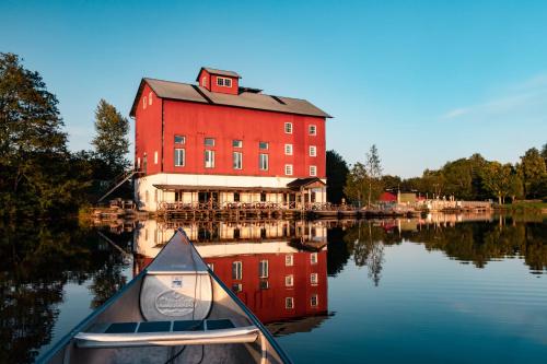 een boot in het water voor een groot rood gebouw bij Upperud 9:9 in Åsensbruk