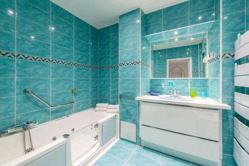 La salle de bains est pourvue de carrelage bleu, d'une baignoire et d'un lavabo. dans l'établissement The Queen, à Nice
