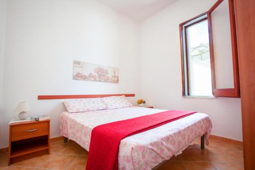 a bedroom with a bed with a red blanket on it at Casa Viga in Tre Fontane