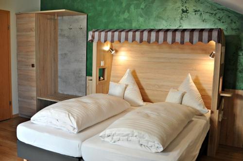 a bed with a wooden headboard in a room at Hotel Restaurant Bürgerklause Tapken in Garrel