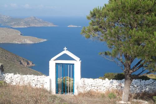 a small white chapel with a cross and a tree at Costareli in Fourni Ikarias