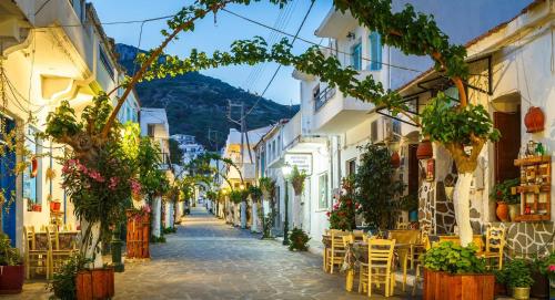 an alley in a town with tables and chairs at Costareli in Fourni Ikarias