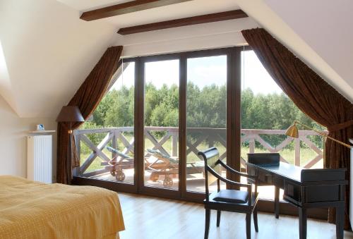 a bedroom with a desk and a balcony with a view at Hotel SPA Dr Irena Eris Wzgórza Dylewskie - Siedliska in Wysoka Wieś