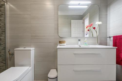 une salle de bain blanche avec un lavabo et un miroir dans l'établissement Apartamento Acantilados, à Acantilado de los Gigantes