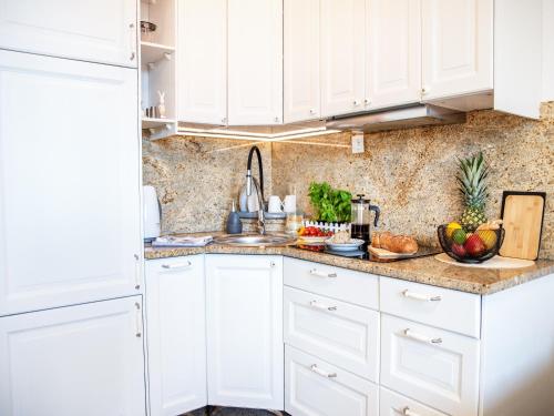 a white kitchen with white cabinets and fruits on the counter at Apartament Sunset Boulevard z tarasem dla 4 gości in Gdynia
