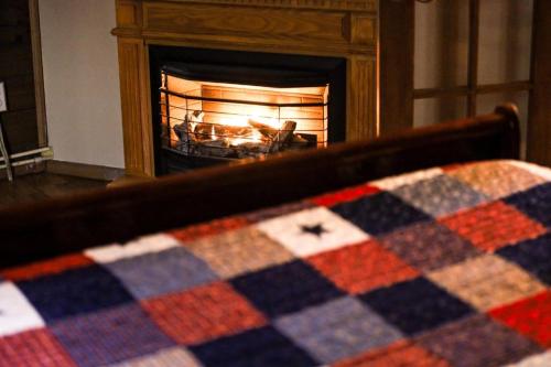 a bed with a checkered blanket in front of a fireplace at Avenwood Cabins in Logan