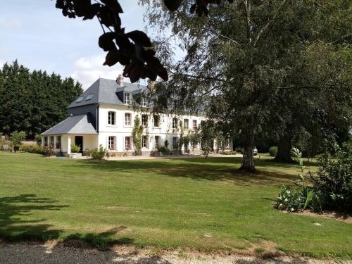 a large white house with a tree in the yard at Manoir du Clap in La Cerlangue