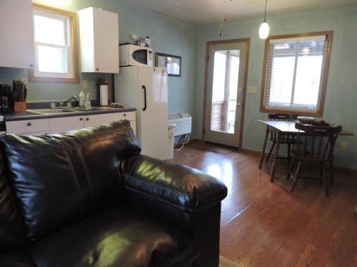 a living room with a leather couch and a kitchen at Avenwood Cabins in Logan