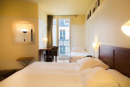 a hotel room with two beds and a desk and a window at Hôtel Quartier Latin in Paris