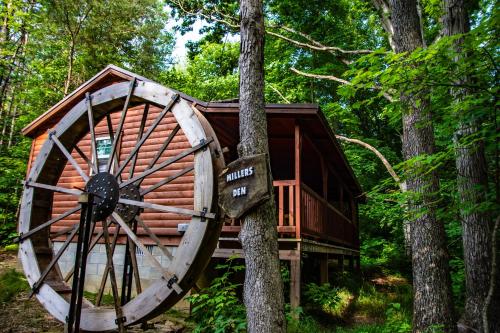 a tree house in the woods with a large wheel at Avenwood Cabins in Logan