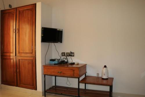 a room with a dresser and a tv on a wall at East Coast in Trivandrum